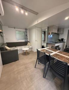 a kitchen and living room with a table and a couch at Mobil Home SIBLU VALRAS PLAGE in Sérignan