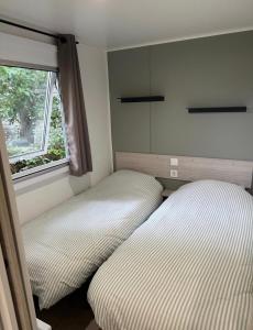 a bedroom with two beds next to a window at Mobil Home SIBLU VALRAS PLAGE in Sérignan +25 photos