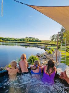 a group of children in a hot tub next to a lake at Agro Zahary in Miastko