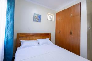 a bedroom with a white bed and wooden cabinets at SereneKey Stays in Kigo