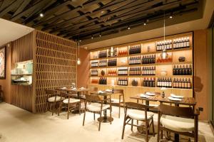 a restaurant with tables and chairs and a wall of wine bottles at Armerun Hotel Rijeka in Rijeka
