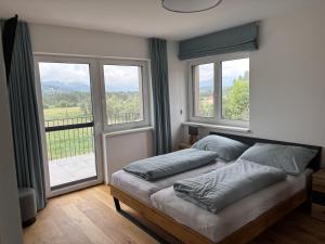 a bedroom with a bed with two pillows and windows at Panorama-Lodge Mittagskogel in Ledenitzen