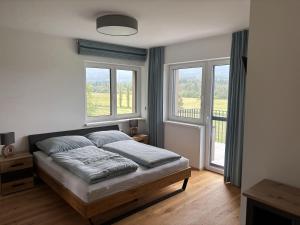 a bedroom with a bed and two windows at Panorama-Lodge Mittagskogel in Ledenitzen