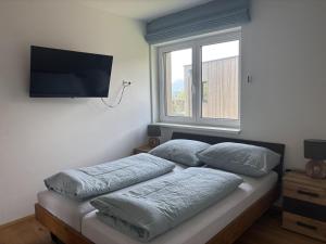 a bedroom with a bed with pillows and a flat screen tv at Panorama-Lodge Mittagskogel in Ledenitzen