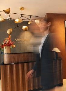 a man in a suit walking past a counter at Armerun Hotel Rijeka in Rijeka