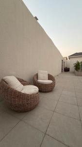 two wicker chairs sitting next to a wall at شاليهات أفق in Jeddah