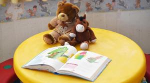 two teddy bears sitting on a yellow table with an open book at Brasilia Sweet Home in Cesenatico