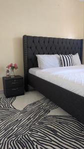 a bedroom with a bed with a black headboard and a rug at Cozy Homes in Bungoma