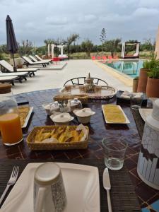 a table with food and drinks on top of a pool at Villa Loanaelle in Marrakesh