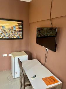 ein Zimmer mit einem Tisch und einem Fernseher an der Wand in der Unterkunft Westreams Hotel in New Weija