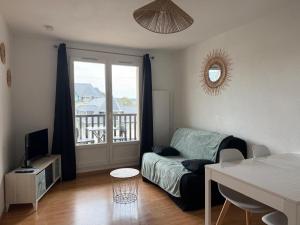 a living room with a couch and a balcony at T2, accès direct plage, proche thalasso in Cabourg