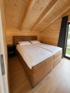 a large bed in a room with a wooden ceiling at Nassfeld Chalet in Rattendorf