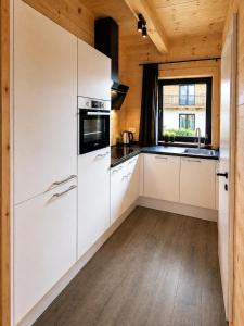 a kitchen with white appliances and a wooden ceiling at Nassfeld Chalet in Rattendorf