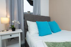 a bedroom with a bed with blue pillows and a table at Open Mind Property - Spacious 2BR Flat City Views in Portsmouth