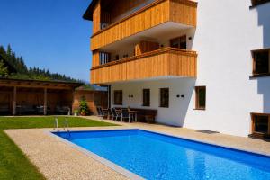 a villa with a swimming pool in front of a house at Aparthotel Iris - inklusive Wildschönau Premium Card in Auffach