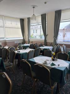 a dining room with tables and chairs and windows at Ashley Court Hotel in Torquay