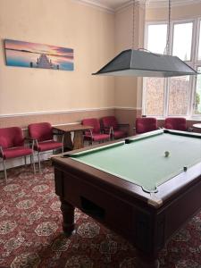 a pool table in a room with red chairs at Ashley Court Hotel in Torquay +7 photos