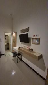 a living room with a tv on the wall at Mulyanus Hotel by Calli Rooms in Wirolegi