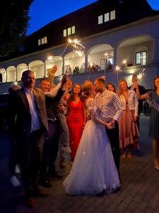 a bride and groom posing for a picture with their wedding party at Kaštieľ Čičmany in Čičmany