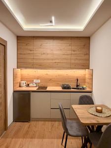 a kitchen with wooden cabinets and a table and chairs at Taca 1 - Airport apartman in Surčin +14 photos