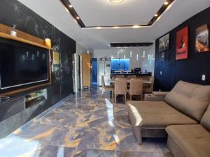 a living room with a tv and a couch and a table at Casa Vale do Sal 2 in Salinópolis