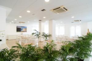 a large room with tables and chairs and plants at Hotel Corallo in Pietra Ligure