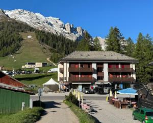 a building with a parking lot in front of a mountain at Passo Carezza Club Apartment in Carezza al Lago