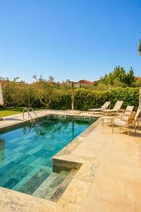 a swimming pool with lounge chairs next to at Zeusplace Magic Pool Villa in Aigínion