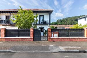 a house with a black gate and a fence at Casa independiente entre mar y montaña in Puente San Miguel