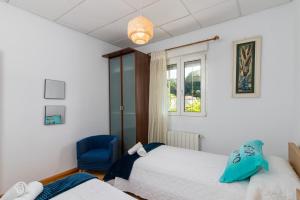 a bedroom with two beds and a blue chair at Casa independiente entre mar y montaña in Puente San Miguel +27 photos