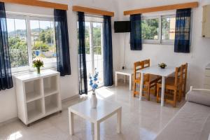 a living room with a table and chairs and windows at Blue Dolphin Aegina in Vaia
