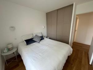 a bedroom with a large white bed with blue pillows at Appartement avec piscine chauffée et Tennis proche Deauville in Touques +16 photos