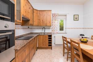 a kitchen with wooden cabinets and a table with chairs at Casa independiente entre mar y montaña in Puente San Miguel