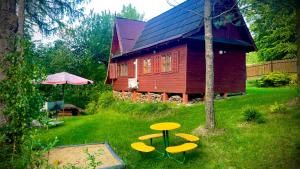 a wooden house with a table and chairs in the yard at Leśny Zakątek Nowy Wiśnicz in Nowy Wiśnicz