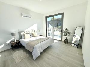 a white bedroom with a bed and a mirror at Villa Tuludis in Drousha