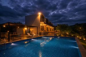 a swimming pool in front of a house at night at VANVASS - A Forest Resort By Rovers in Rāma