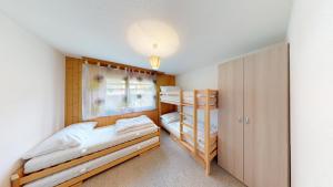 a small bedroom with two bunk beds and a window at Haus Belstar A in Naters