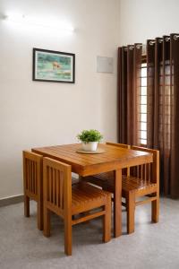 a wooden table and chairs with a potted plant on it at Mistnview By SHELTERS in Meppādi