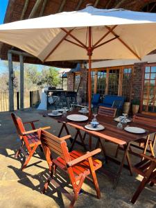 a wooden table and chairs under an umbrella at Kudu Plaas - Wildlife on your doorstep in Beestekraal
