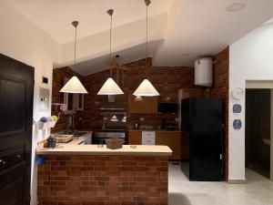 a kitchen with a black refrigerator and a brick wall at Villa Amoun,Beachfront Villa & sea view,North Coast in Sidi Kirayr