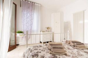 a white bedroom with a large bed and a table at Villa Jadì Sottomarina in Chioggia