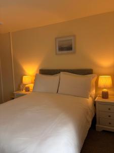 a bedroom with a large white bed with two lamps at Fahertys bar rooms in Oughterard +23 photos