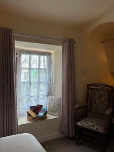 a bedroom with a bed and a window with a chair at Fahertys bar rooms in Oughterard