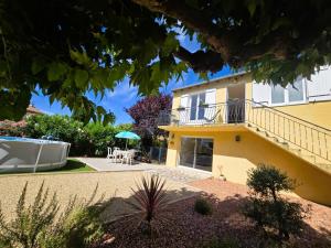 a yellow house with a balcony and a patio at Le Balcon de Cournon, piscine, jardin, clim à 15 min de plages in Cournonterral