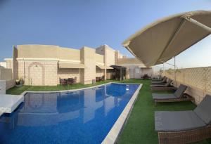 a pool with chairs and an umbrella next to a building at Al Maha Int Hotel Oman in Ghukra