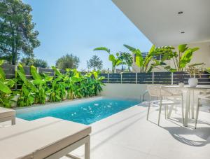 an outdoor patio with a swimming pool and a table and chairs at Calista Horizon by Booking Kottas in Kallithea Halkidikis