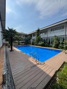 a swimming pool with a wooden deck next to a building at Hotel Elegant 2 in Andizhan