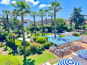 an aerial view of a park with palm trees and umbrellas at Hotel des Mimosas in Juan-les-Pins