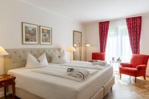 a bedroom with a large white bed and red chairs at Hotel Döllnsee-Schorfheide in Templin