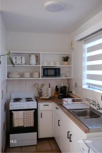 a white kitchen with a stove and a sink at Harbour Lane Stay in Geraldton